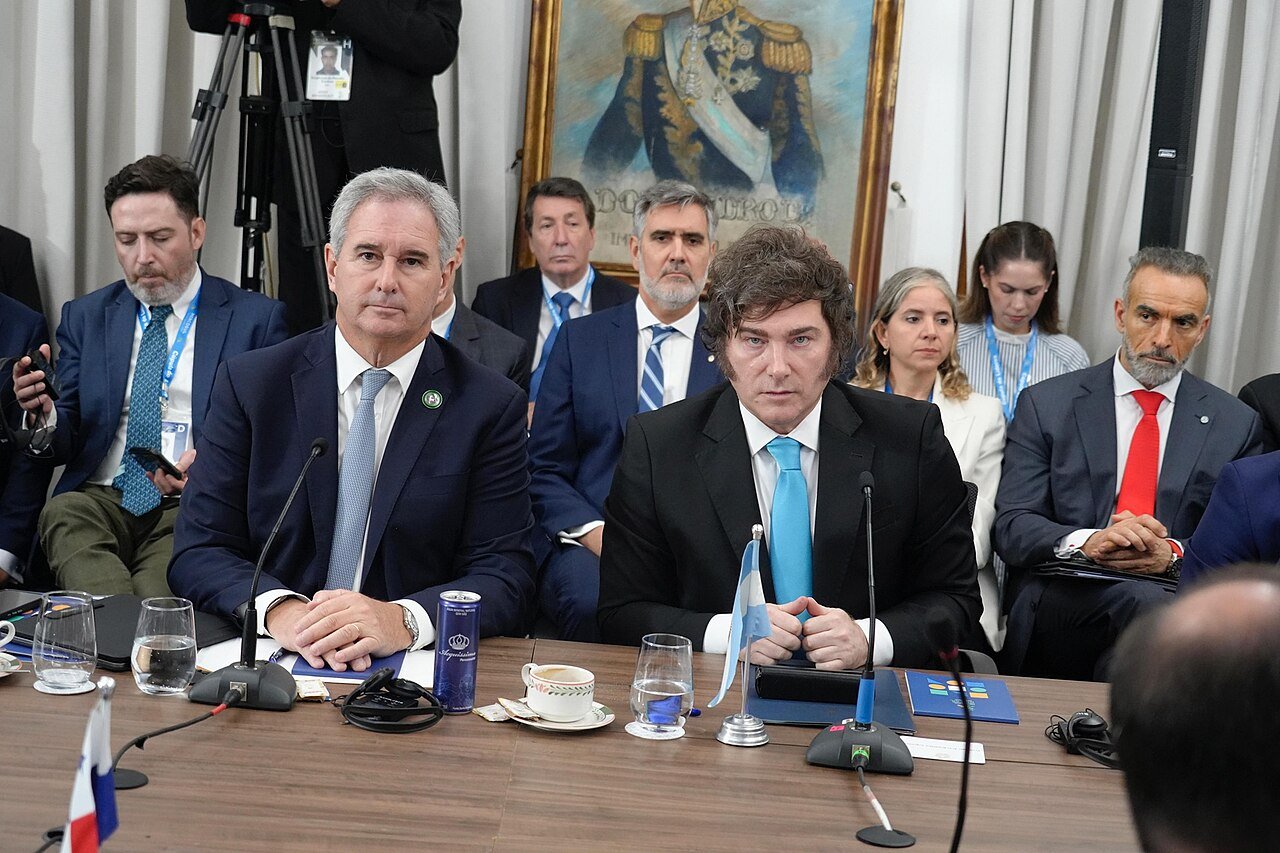 Presidente da Argentina Javier Milei em mesa de reunião com bandeira argentina