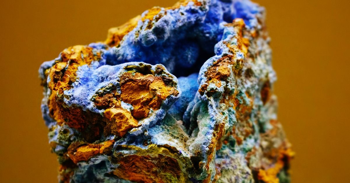 Amostra mineral bruta em plano macro, com faixas azuis e alaranjadas