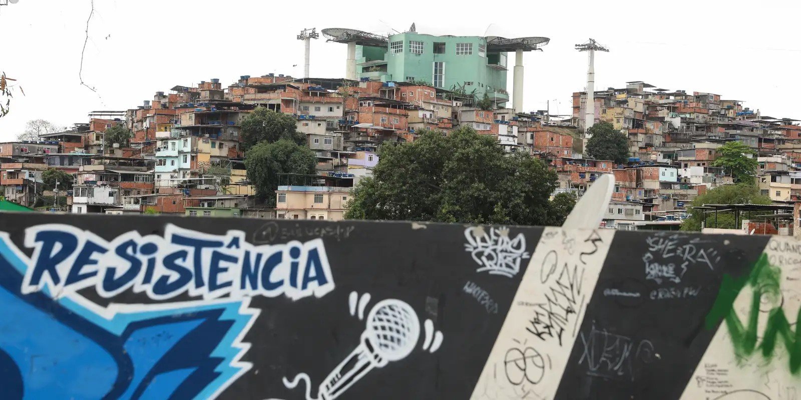 Vista do Complexo do Alemão, no Rio de Janeiro, com estação do teleférico ao fundo e muro grafitado