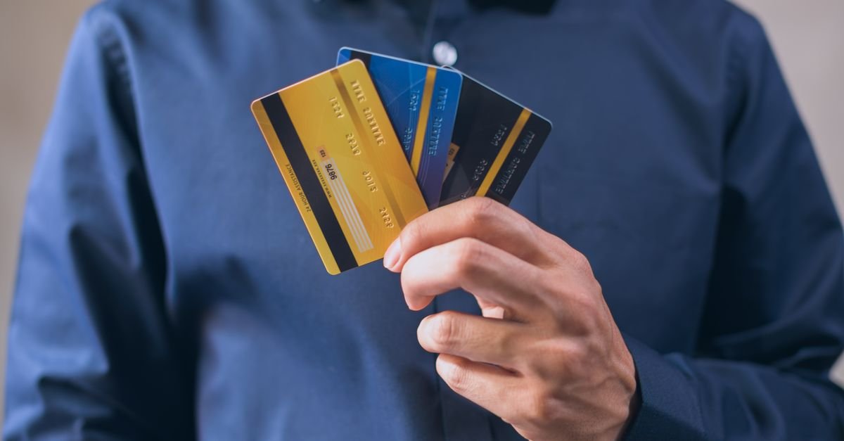 Mão segura três cartões de crédito em leque