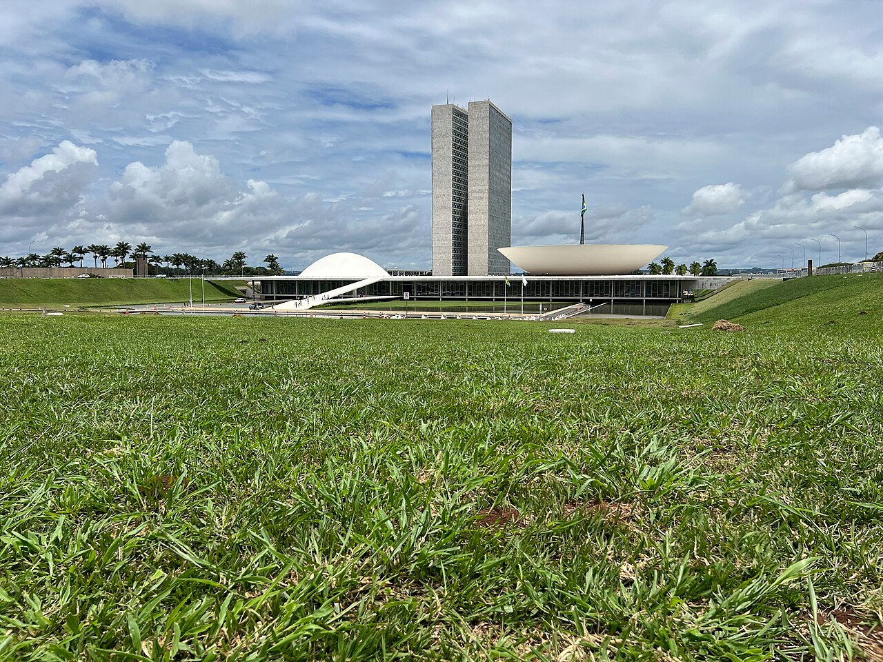 Congresso Nacional em Brasília visto do gramado, com as cúpulas e as torres ao fundo