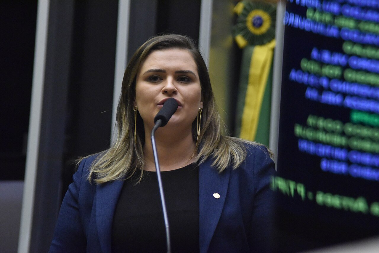 Deputada discursa no plenário da Câmara dos Deputados diante do painel de votação