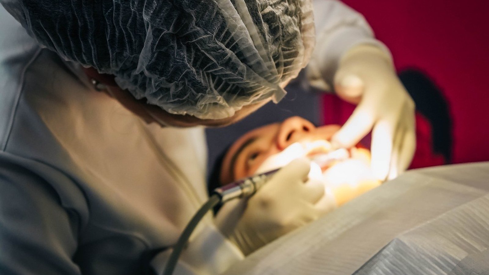 Dentista de touca e máscara em atendimento no Odonto em Ação