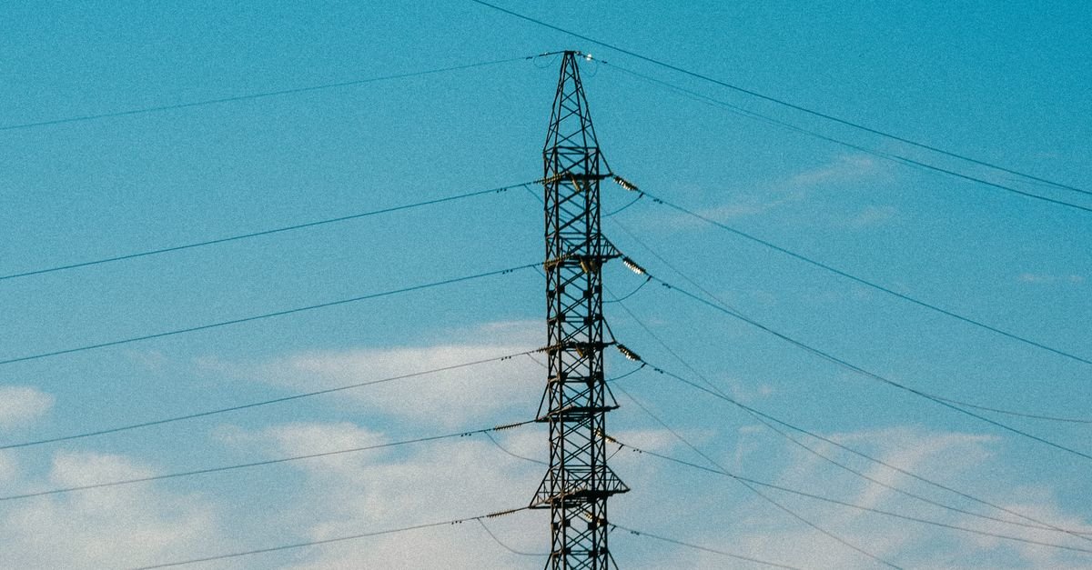 Torre de transmissão de energia elétrica com cabos contra o céu azul