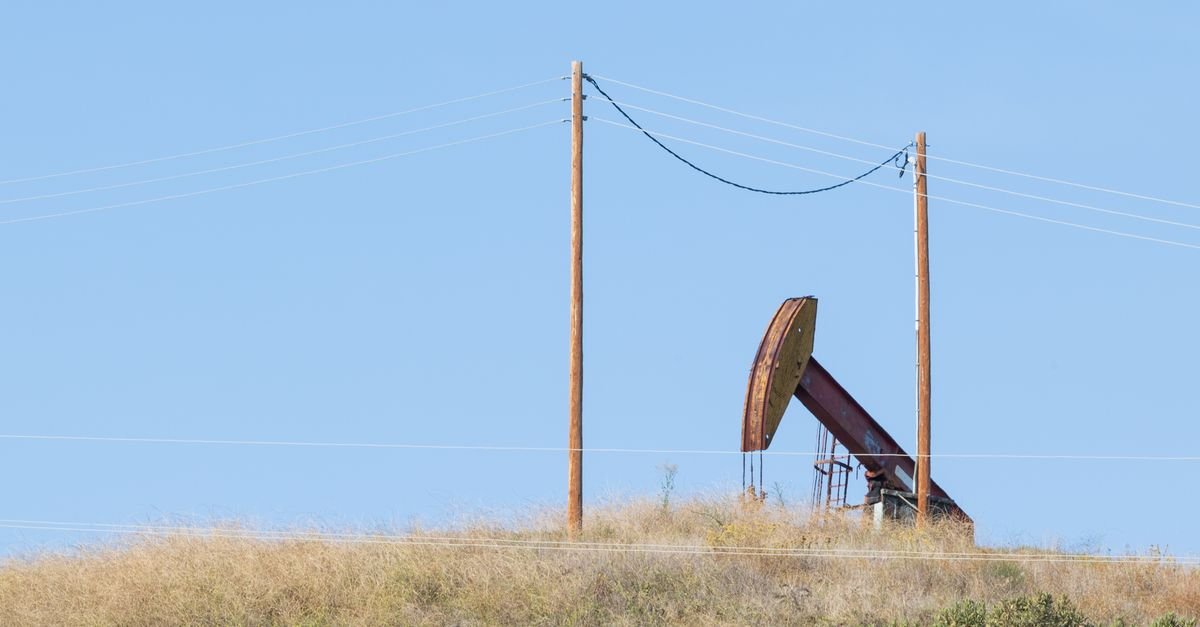 Cavalo de pau de extração de petróleo em campo aberto sob céu azul