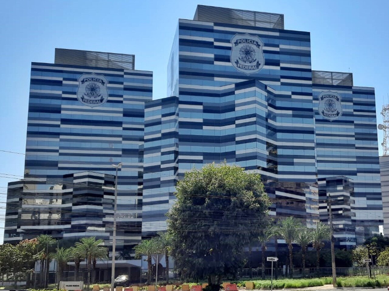 Fachada envidraçada da sede da Polícia Federal em Brasília, com o brasão do órgão nos prédios