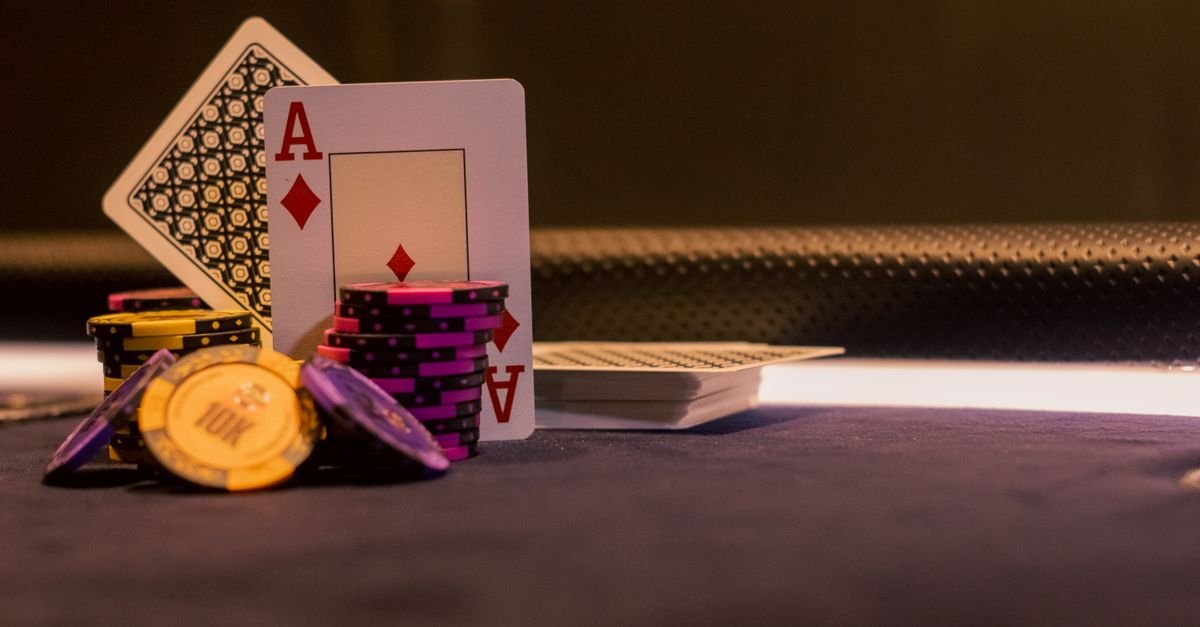 Fichas de jogo empilhadas ao lado de cartas de baralho sobre mesa escura
