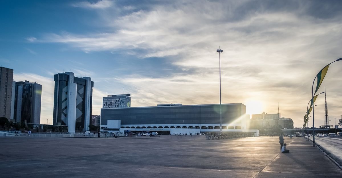 Esplanada em Brasília ao pôr do sol, com prédios e bandeiras
