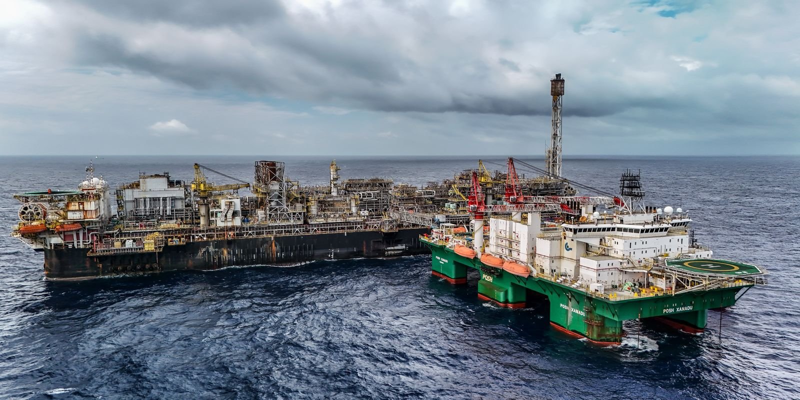 Plataforma de produção de petróleo no mar acompanhada por embarcação de apoio