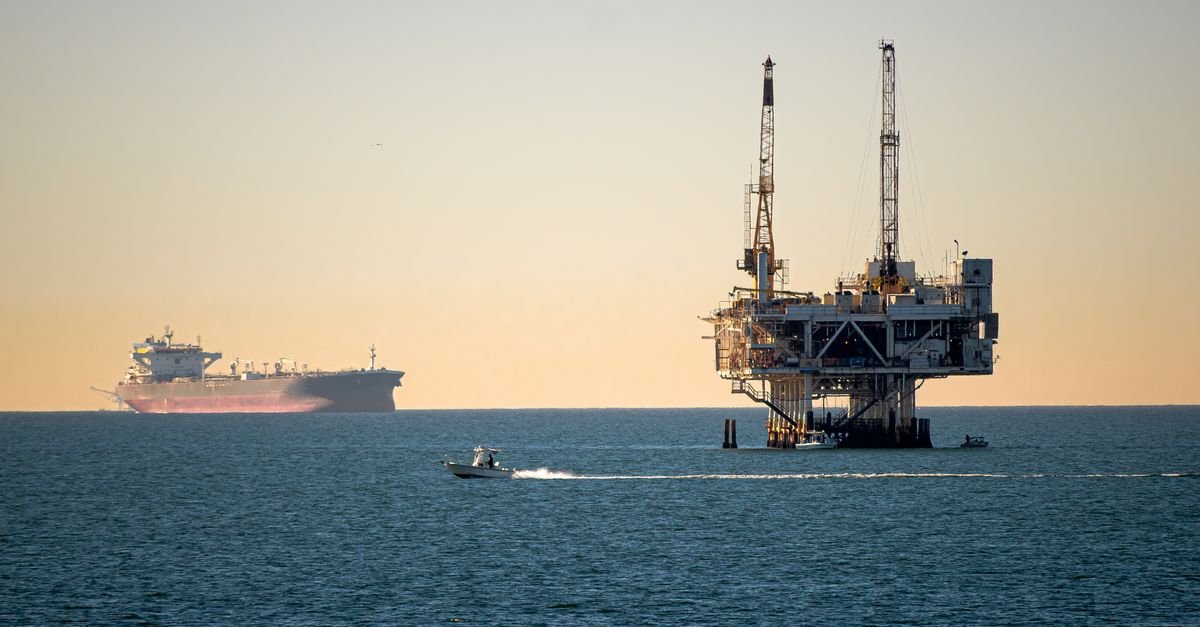 Plataforma de petroleo offshore e navio cargueiro ao entardecer em mar aberto