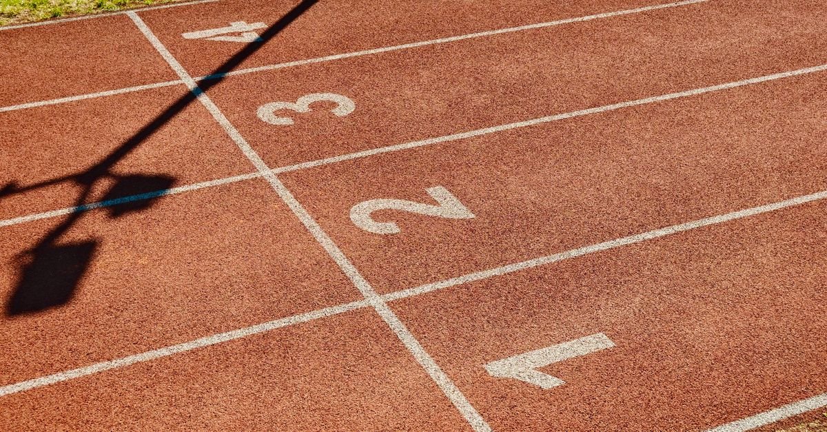 Pista de atletismo vermelha com raias numeradas de 1 a 4 marcadas em branco