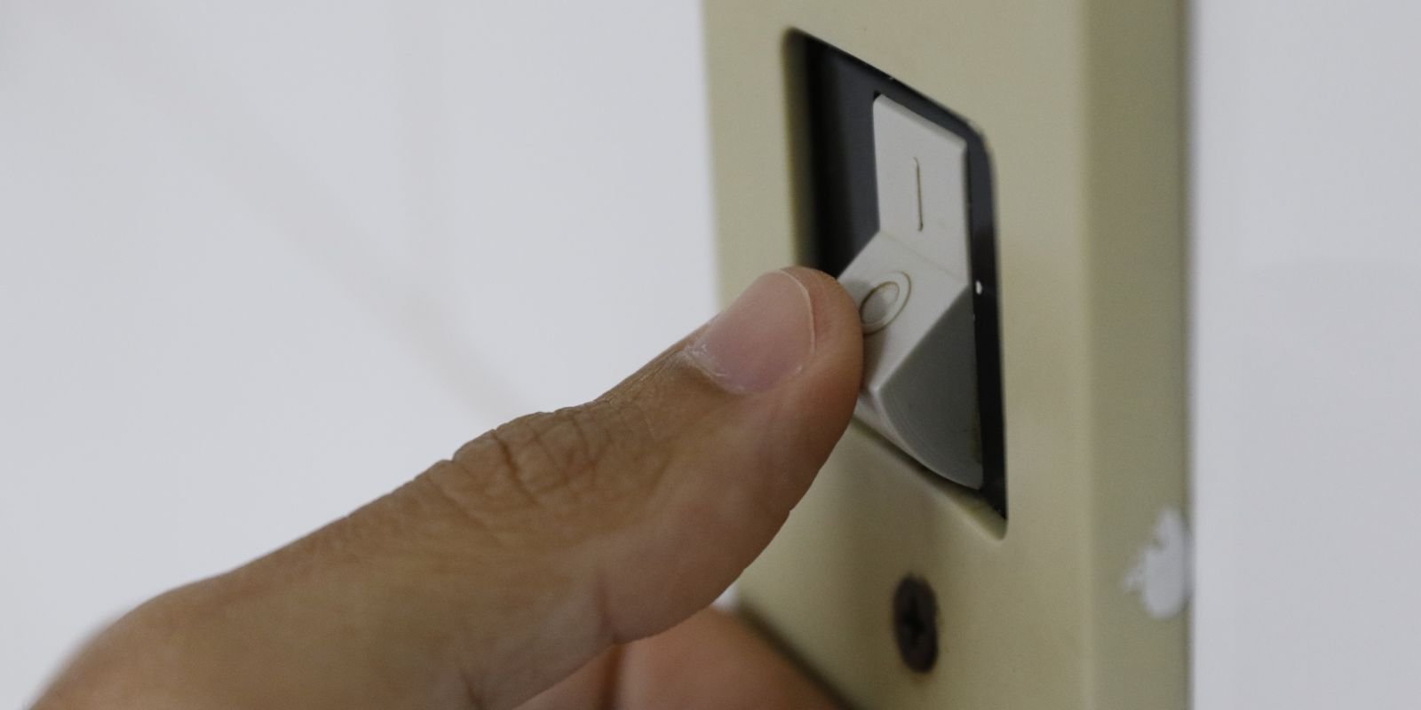 Dedo aciona interruptor de luz na parede de uma residência