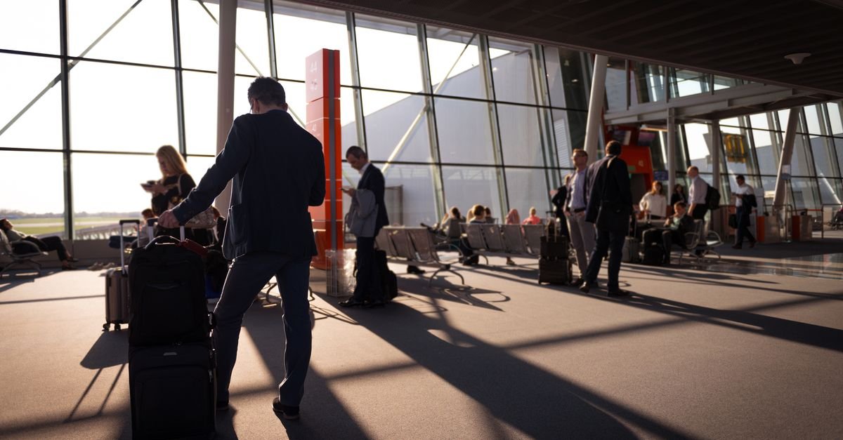 Passageiros com malas caminham no saguão de embarque de um aeroporto
