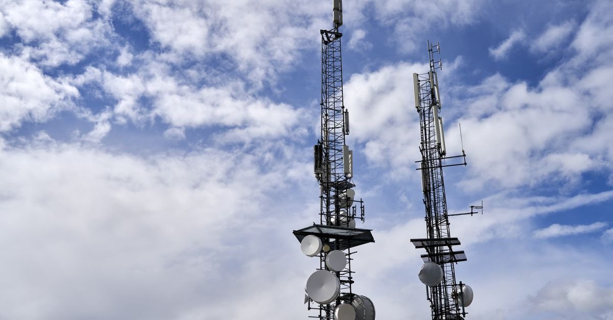 Duas torres de telecomunicações com antenas e antenas parabólicas contra o céu