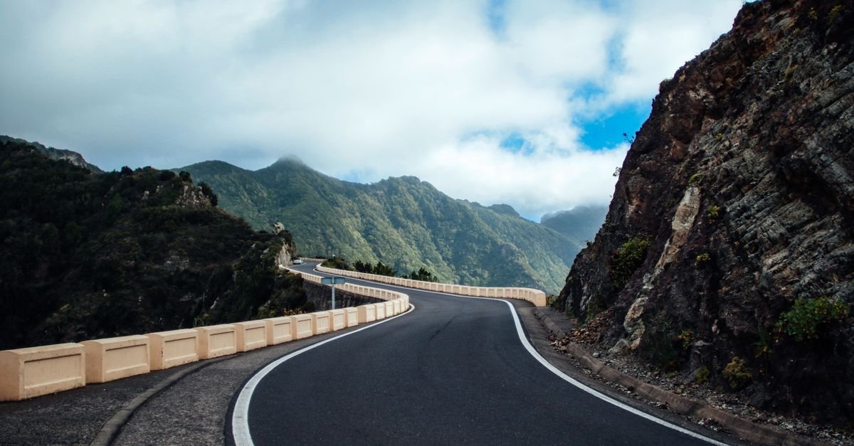 Rodovia asfaltada em curva entre montanhas, sem veículos