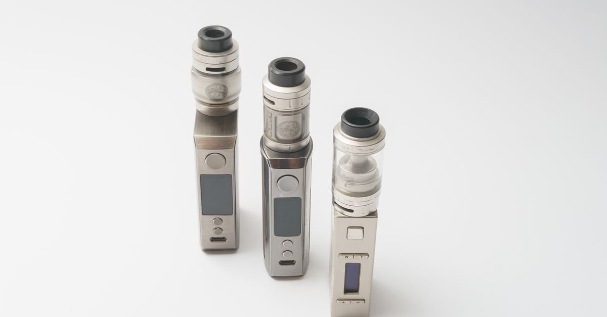 Três dispositivos eletrônicos para fumar, conhecidos como vapes, sobre fundo branco