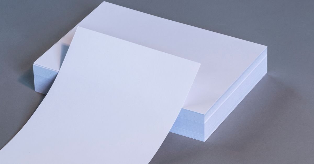 Pilha de folhas de papel em branco sobre superfície cinza