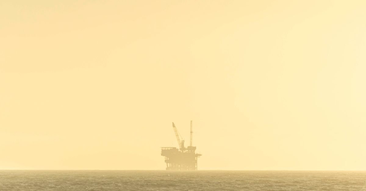 Silhueta de plataforma de petróleo em alto-mar ao entardecer