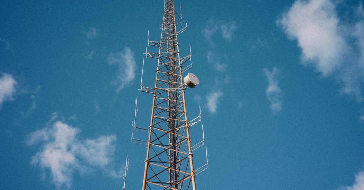 Torre de transmissão de rádio e televisão com antenas vista de baixo contra o céu azul