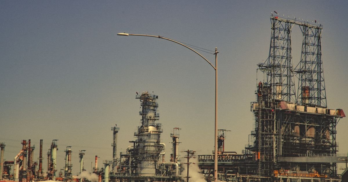 Torres e tubulações de uma refinaria de petróleo vistas de fora da unidade