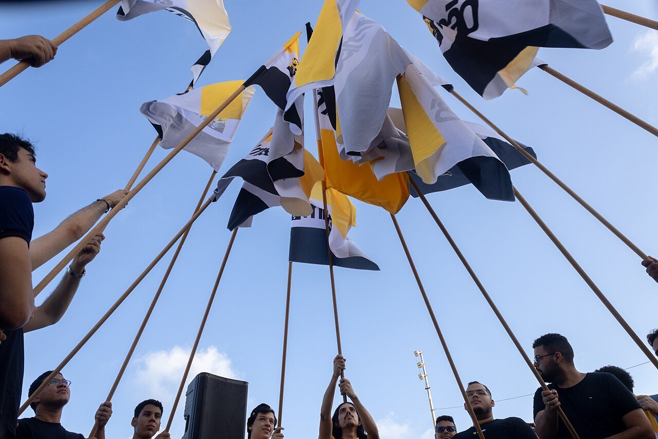 Bandeiras do partido Missao erguidas por apoiadores contra o ceu em ato de campanha