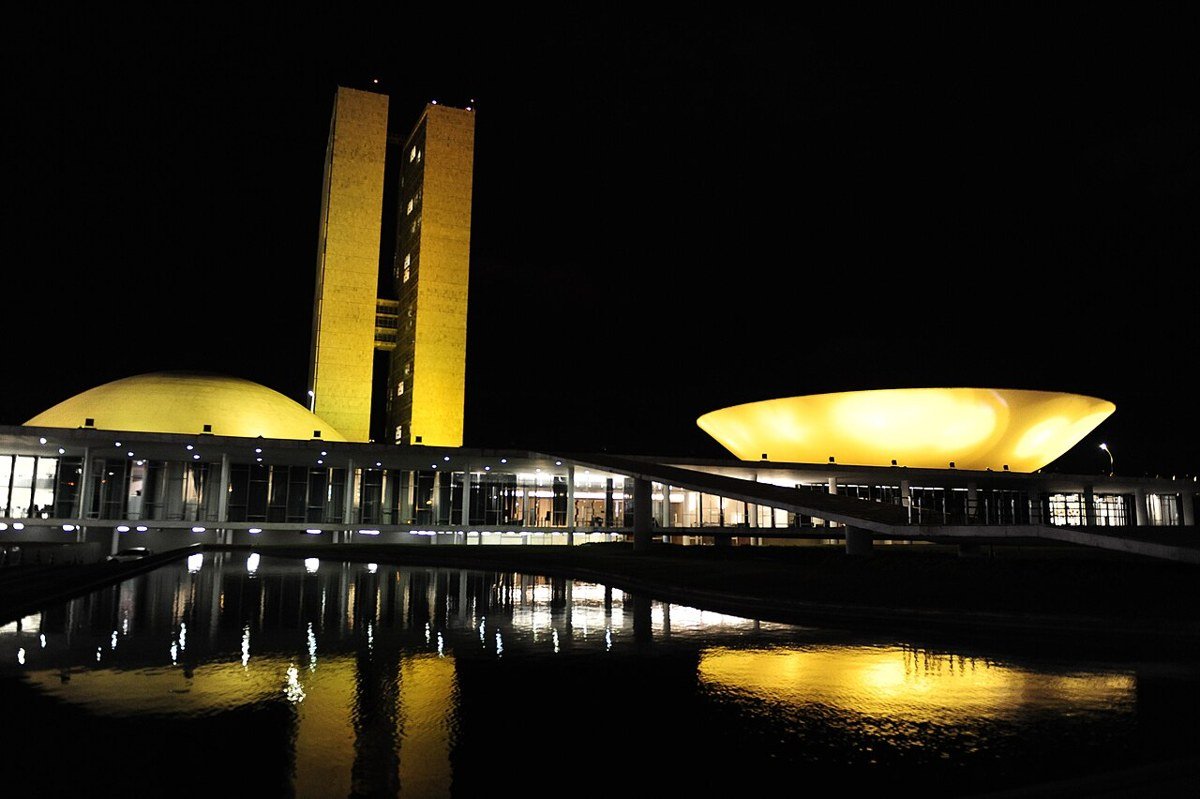 Palácio do Congresso Nacional iluminado à noite, com reflexo no espelho d'água