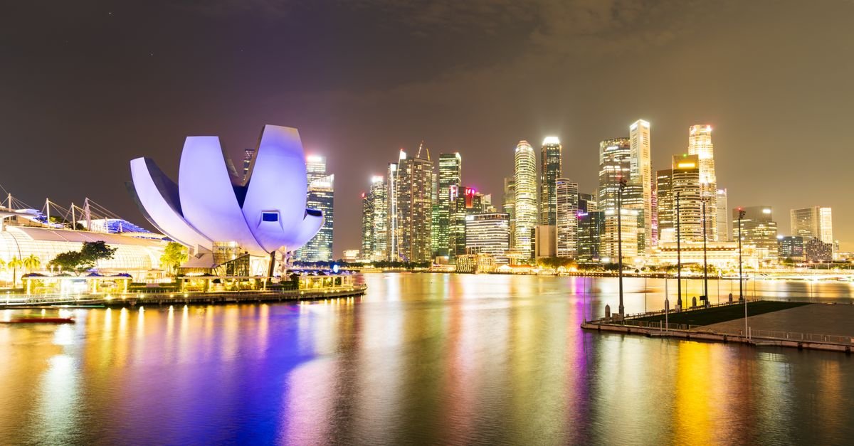 Skyline noturno de Singapura com o Marina Bay iluminado e reflexos na água