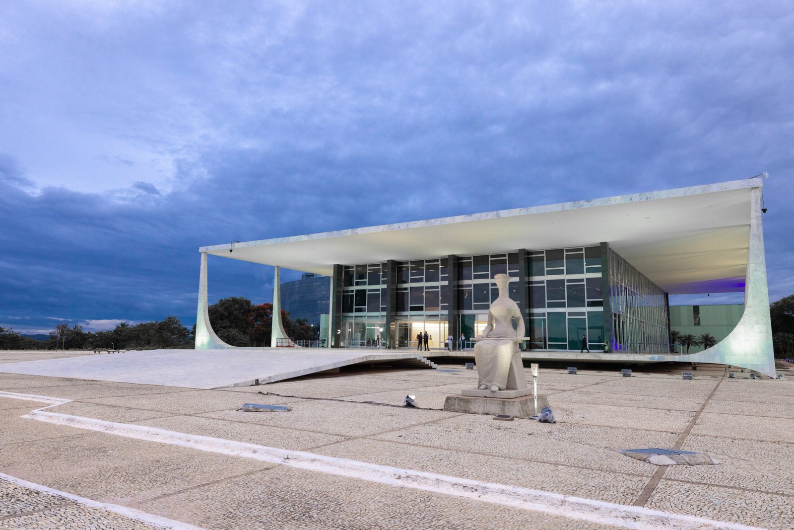 Fachada do prédio do Supremo Tribunal Federal ao entardecer, com a estátua da Justiça em primeiro plano