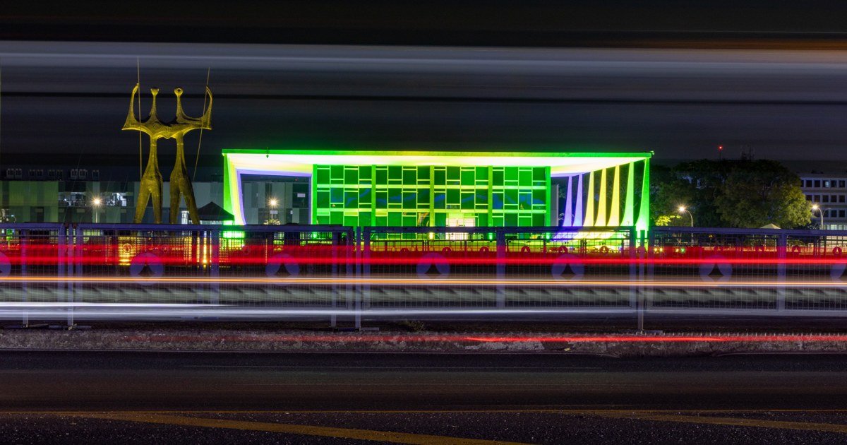 Fachada do edifício-sede do Supremo Tribunal Federal iluminada à noite, com a escultura Os Candangos à esquerda