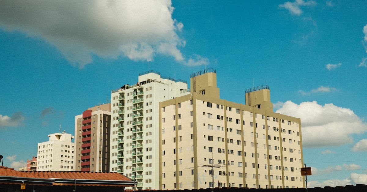 Prédios residenciais com varandas vistos de baixo, sob céu azul