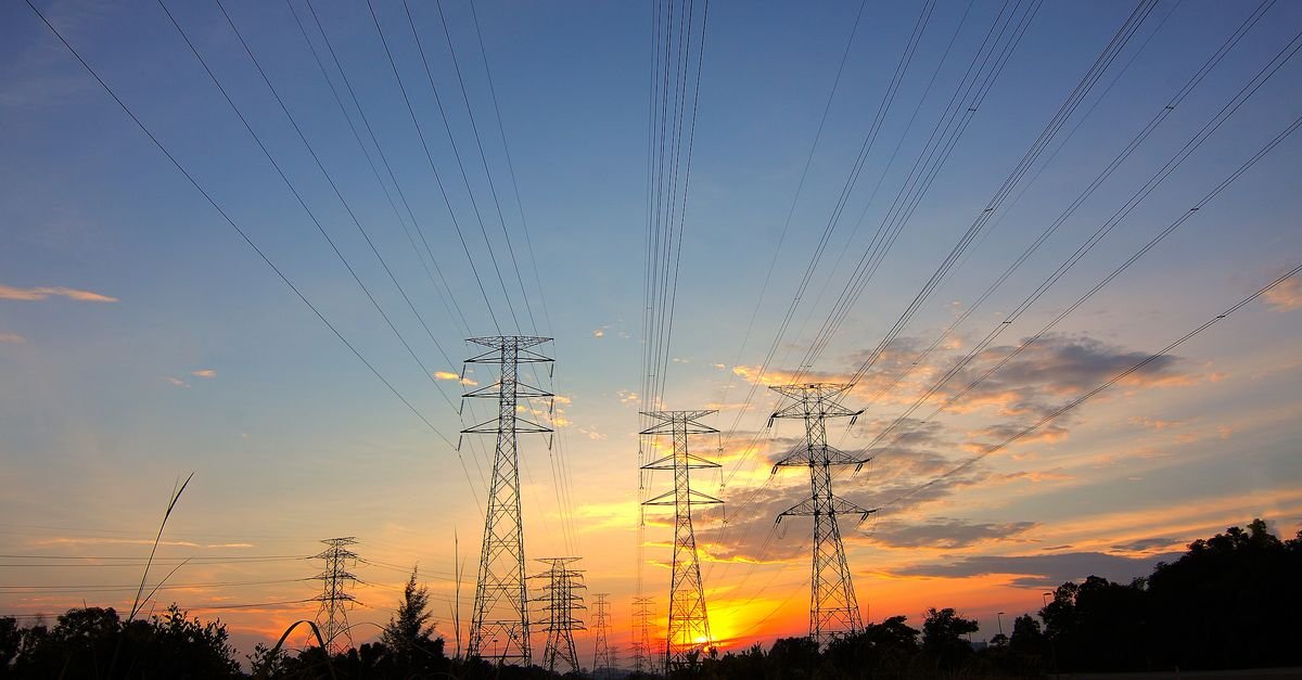 Torres de transmissão de energia elétrica recortadas contra um céu de fim de tarde