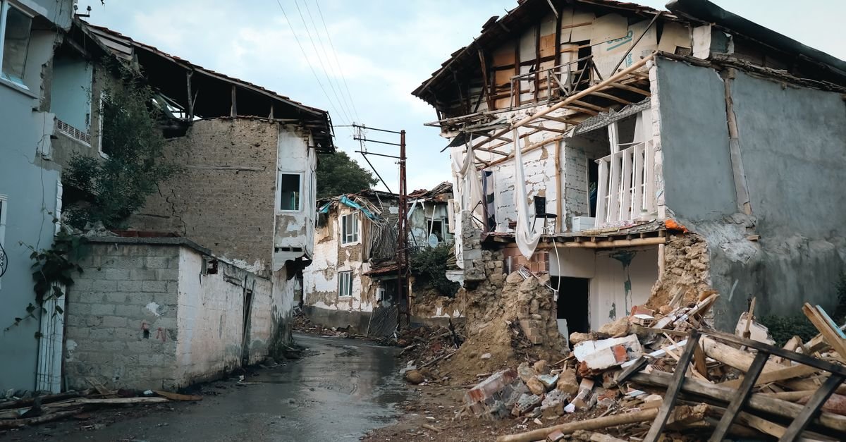 Casas destruídas e escombros em rua estreita após terremoto