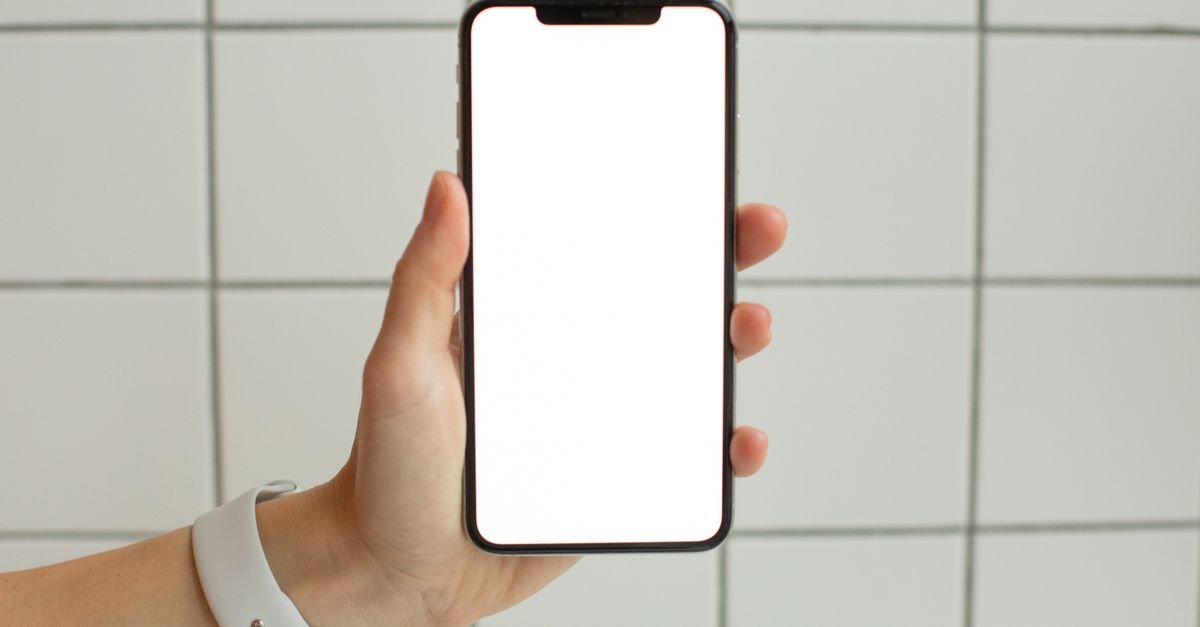 Mão segura um smartphone com a tela em branco, em imagem que ilustra a desativação de um aplicativo