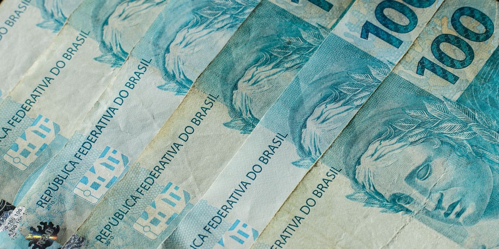 Cédulas de cem reais espalhadas, com a inscrição República Federativa do Brasil