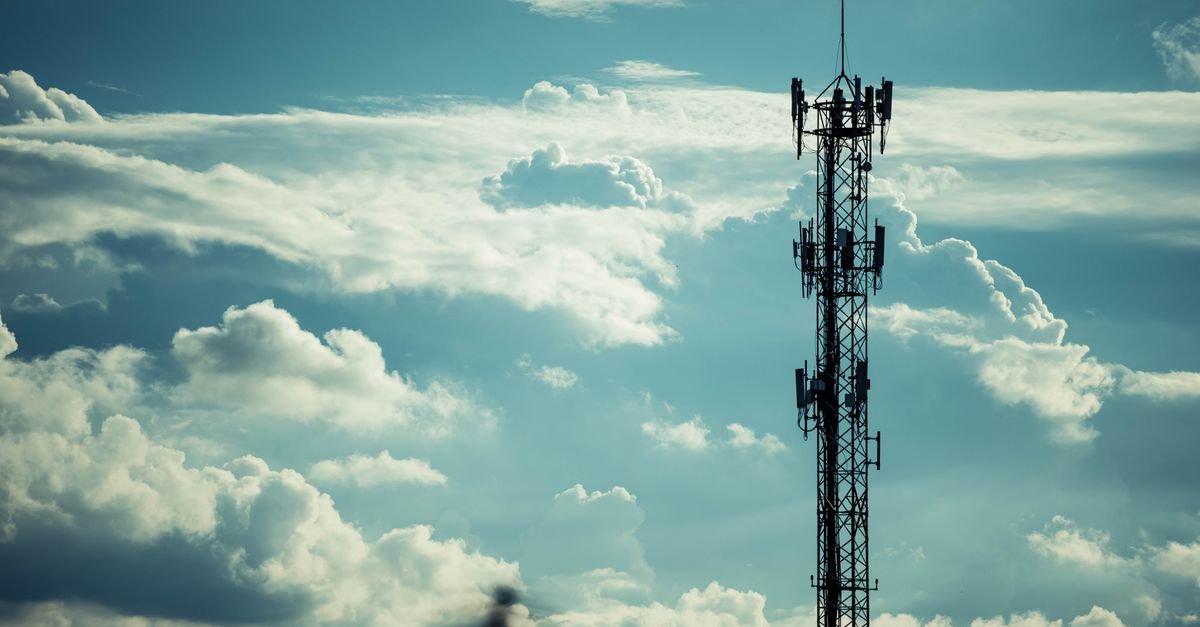 Torre de transmissão em silhueta contra céu nublado ao entardecer