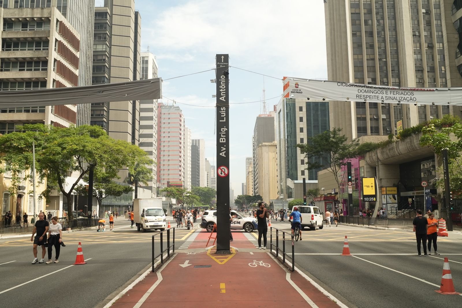 Avenida movimentada em São Paulo com pedestres e ciclofaixa