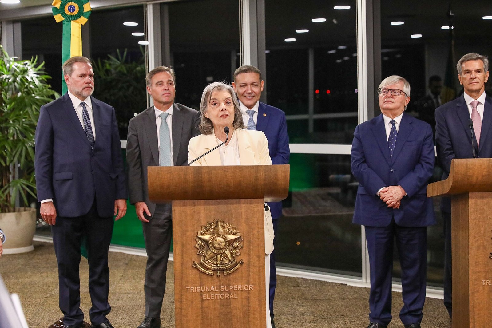 Ministros do Tribunal Superior Eleitoral durante pronunciamento em púlpito com o nome do tribunal, em Brasília