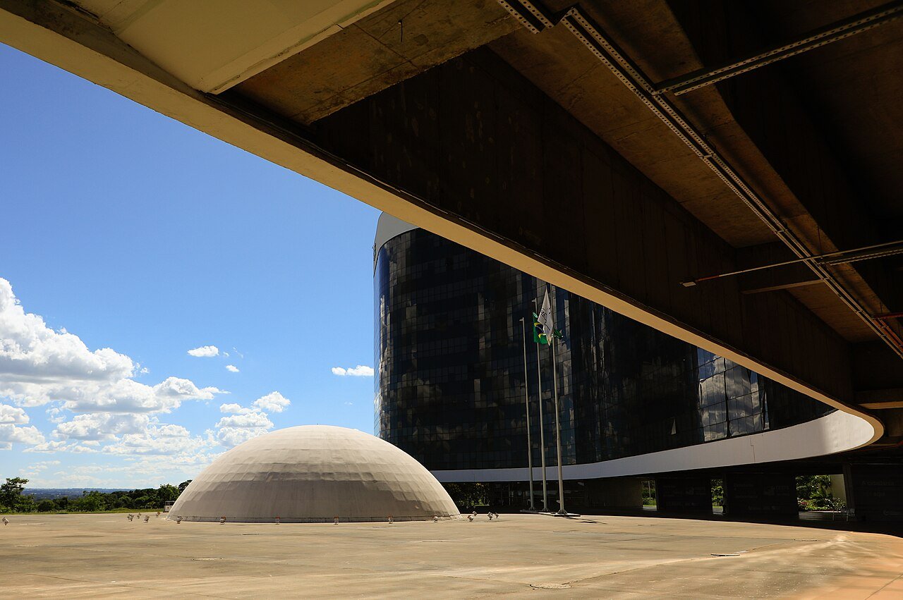 Sede do Tribunal Superior Eleitoral, em Brasília, com a cúpula do plenário e as bandeiras hasteadas em frente à fachada de vidro
