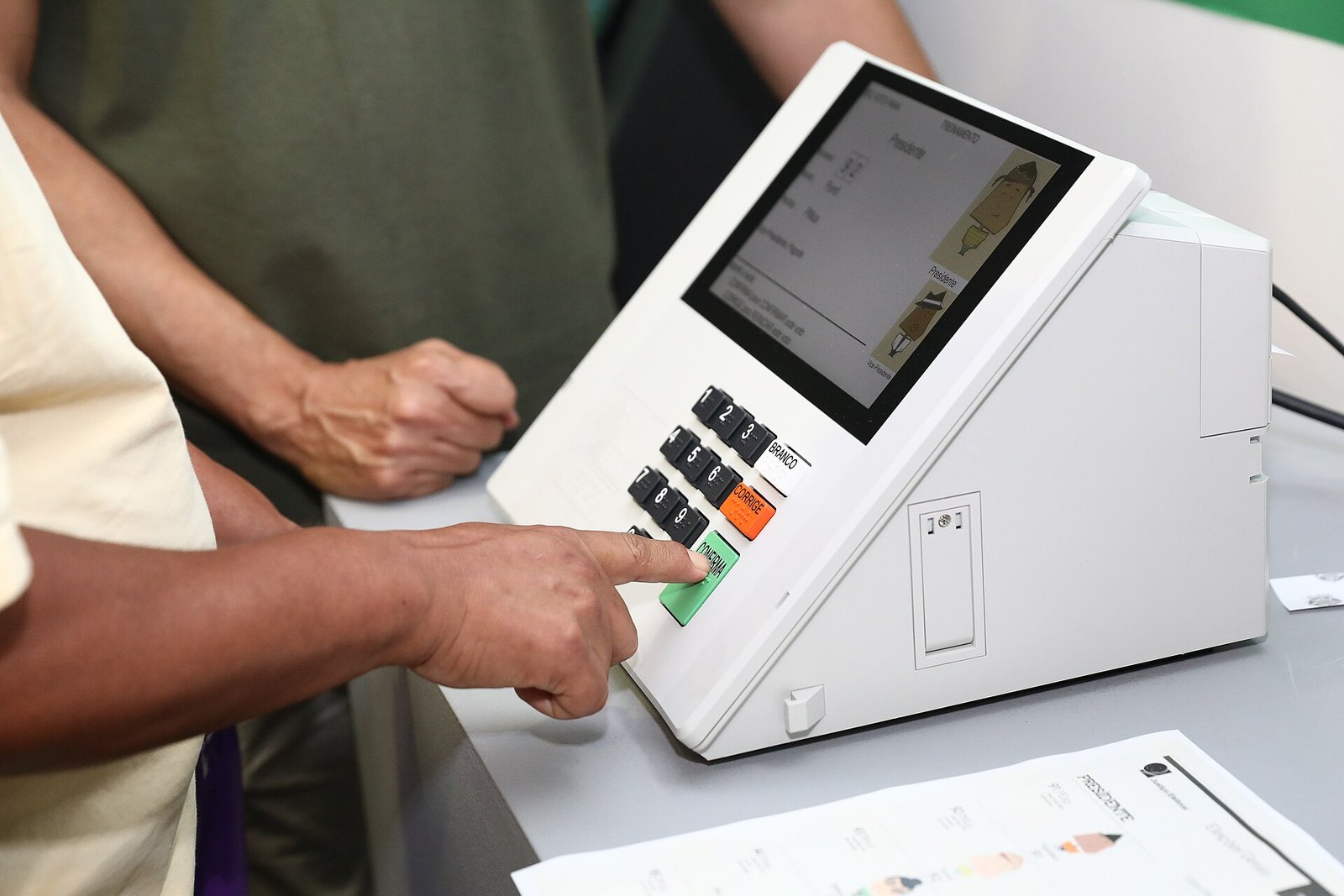 Mão de eleitor pressiona a tecla Confirma de uma urna eletrônica da Justiça Eleitoral