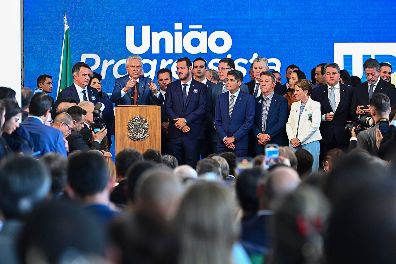 Dirigentes partidários reunidos no palco do lançamento da federação União Progressista, com painel do nome ao fundo
