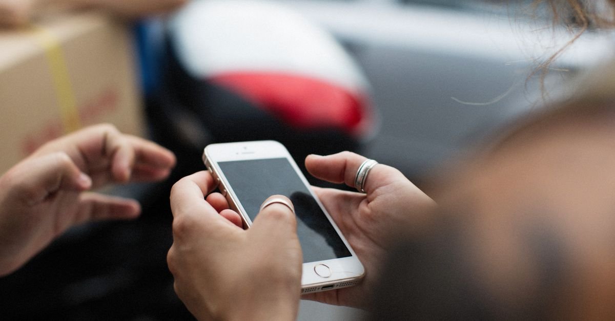 Mãos seguram um celular com a tela apagada